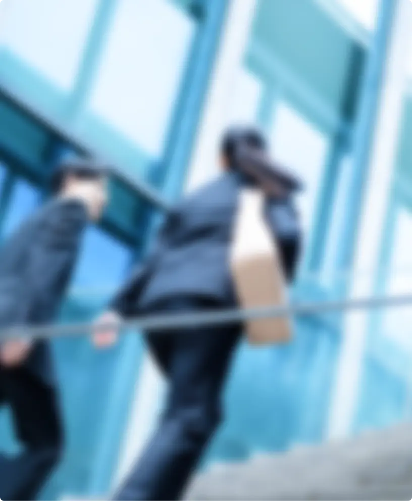 都市のビル前を歩くスーツ姿の人々