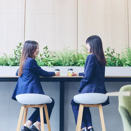 オフィスでコーヒーを飲みながら談笑している若い女性2名。